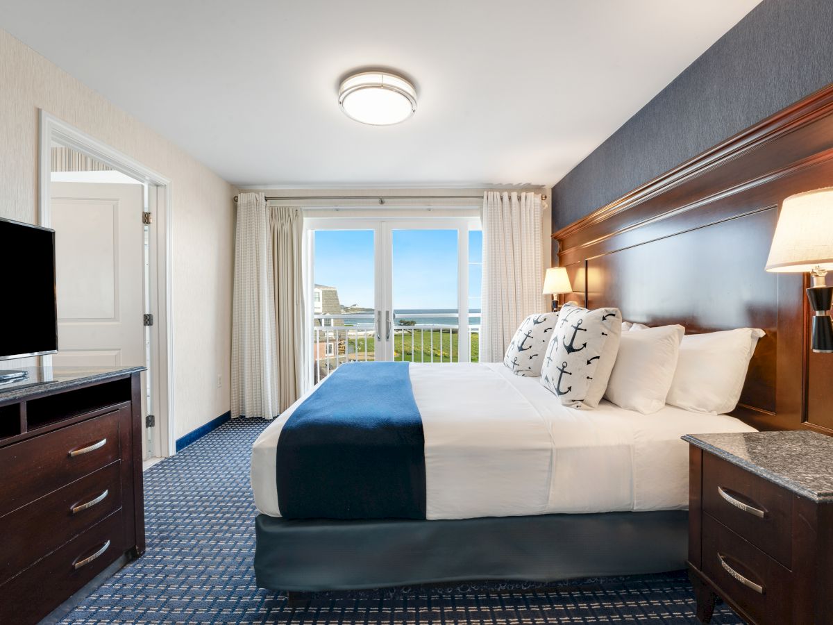 The image shows a well-lit hotel room with a double bed, lamps, a TV on a dresser, and a view of the outdoors through sliding glass doors ending the sentence.