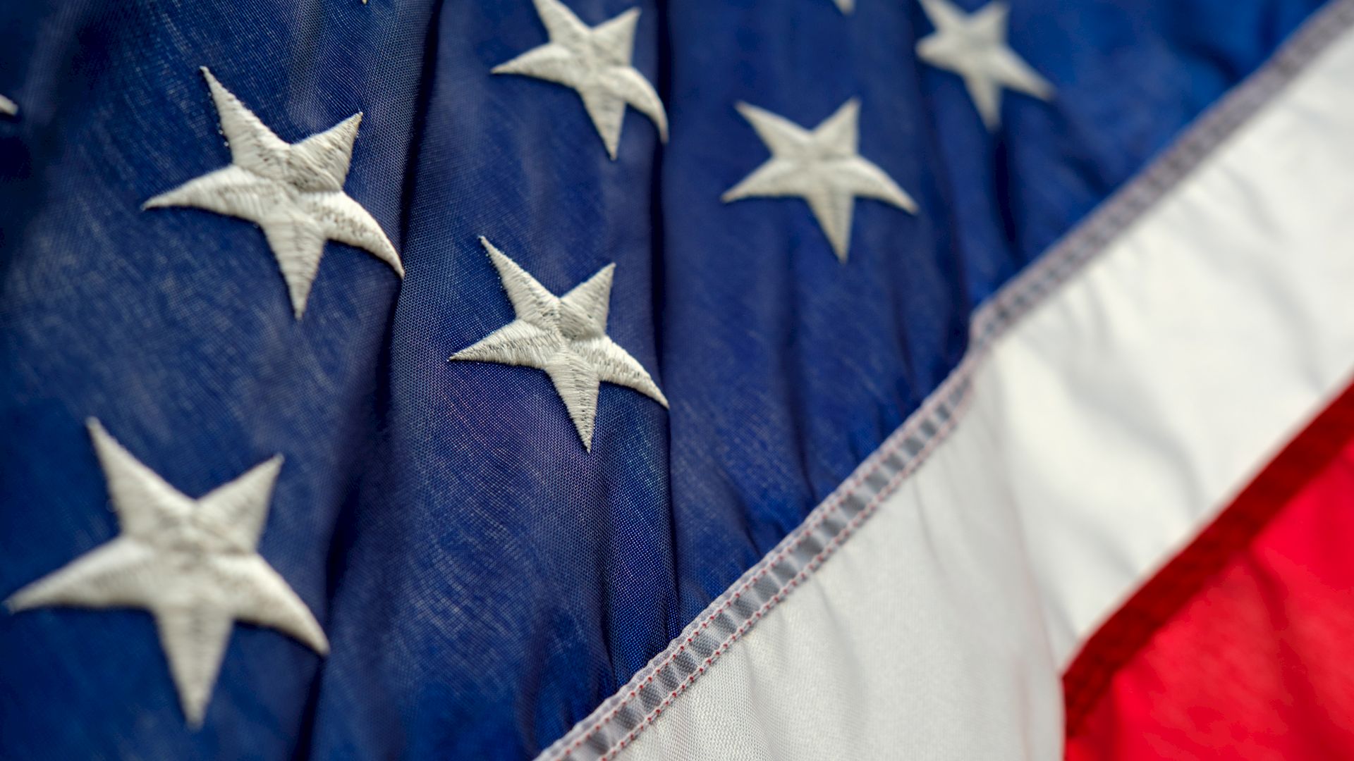 This image shows a close-up of the United States flag, featuring the blue field with white stars and parts of the red and white stripes.