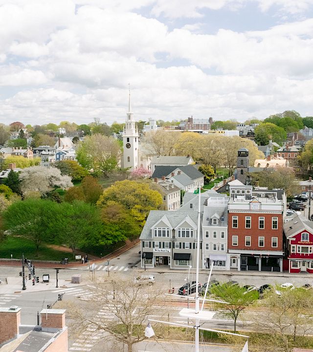 Aerial view of a small town with tree-lined streets, church steeples, and rooftops under a cloudy sky.